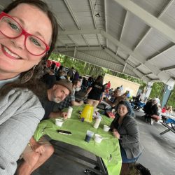 Lysa takes a selfie with Frank and Billie in the background at an event.